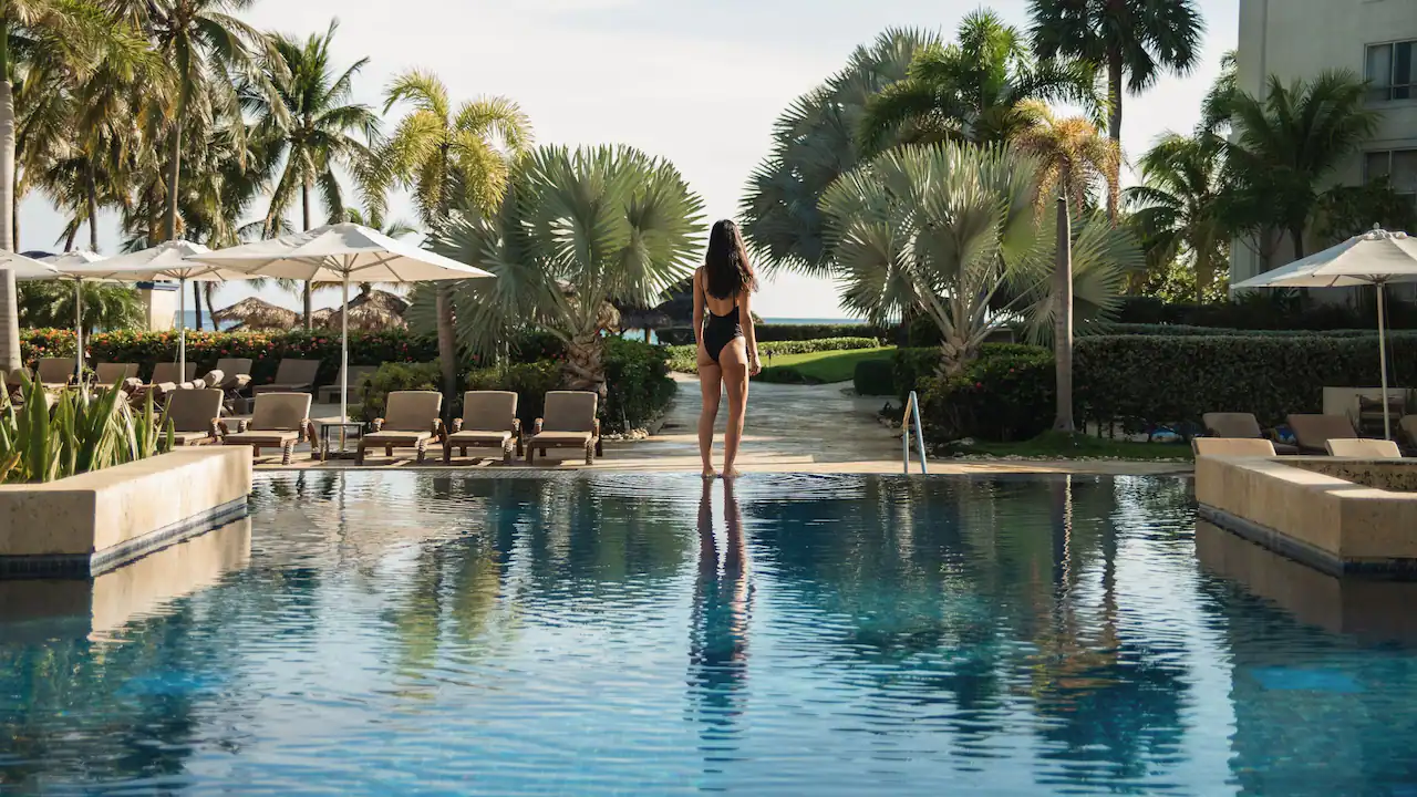 Guest standing beside the adults-only main pool surrounded by palm trees and lounge chairs at Hyatt Zilara Rose Hall.