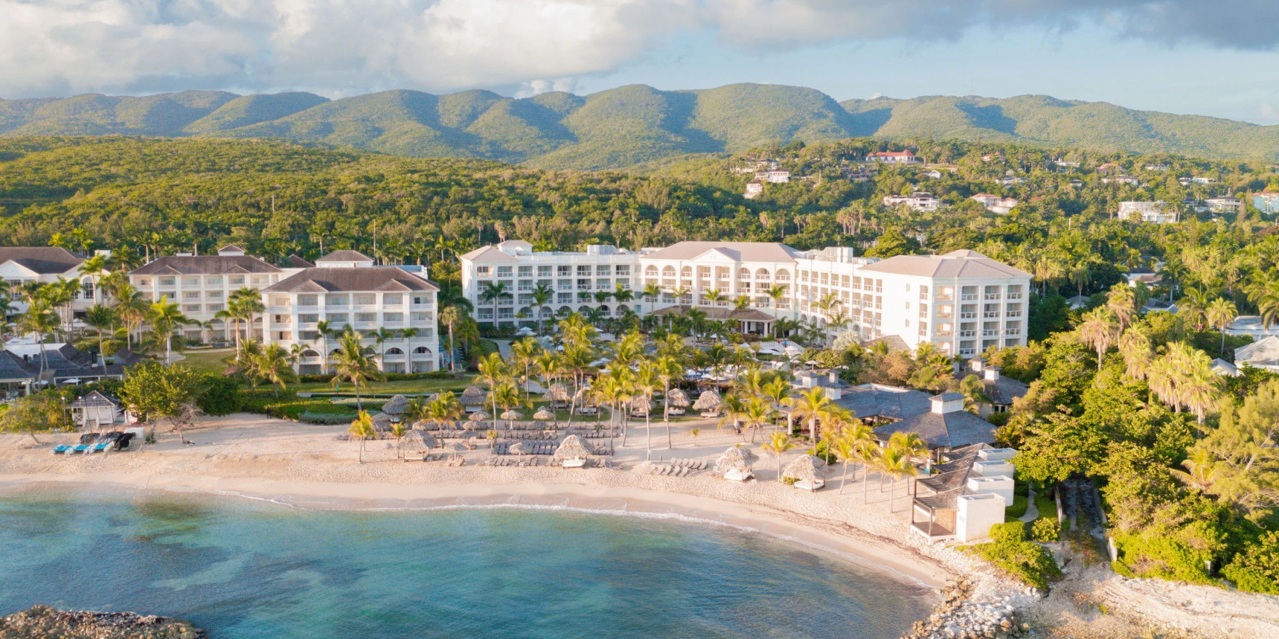 Aerial view of Hyatt Zilara Rose Hall beachfront resort surrounded by turquoise waters and Jamaican mountains.