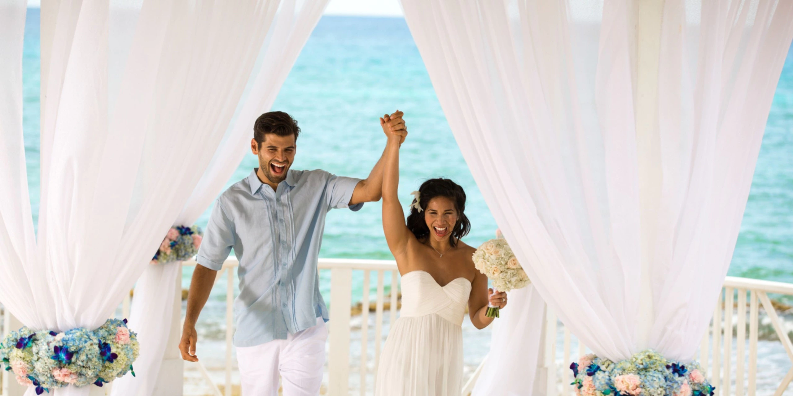 Newlywed couple celebrating after a beachfront wedding ceremony at Hyatt Zilara Rose Hall overlooking the Caribbean Sea.