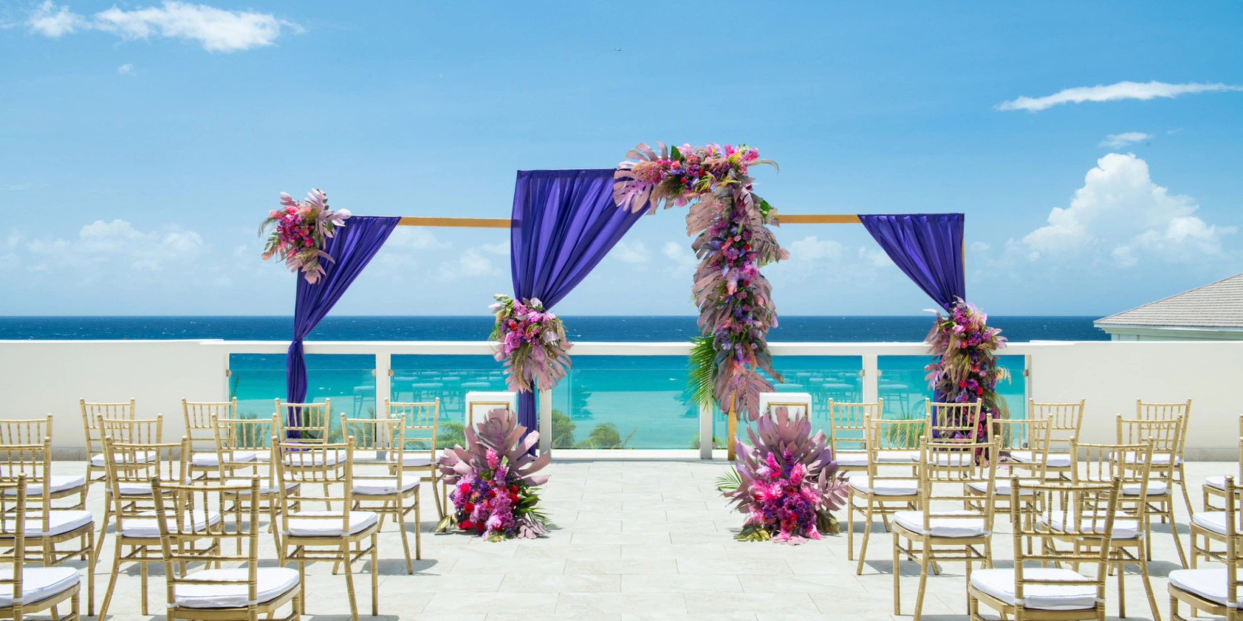 Oceanview wedding ceremony setup with vibrant floral arch on a rooftop terrace at Hyatt Zilara Rose Hall.