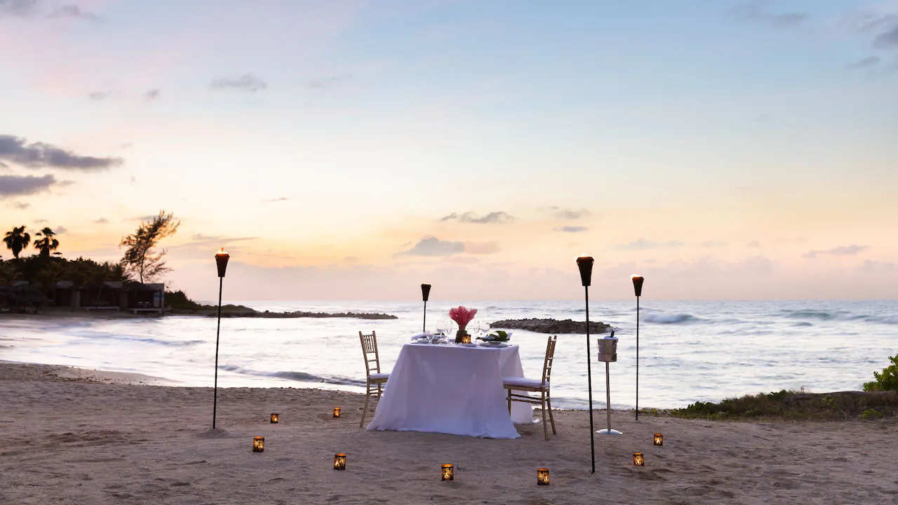Private candlelit dinner setup on the beach at sunset at Hyatt Zilara Rose Hall in Montego Bay.