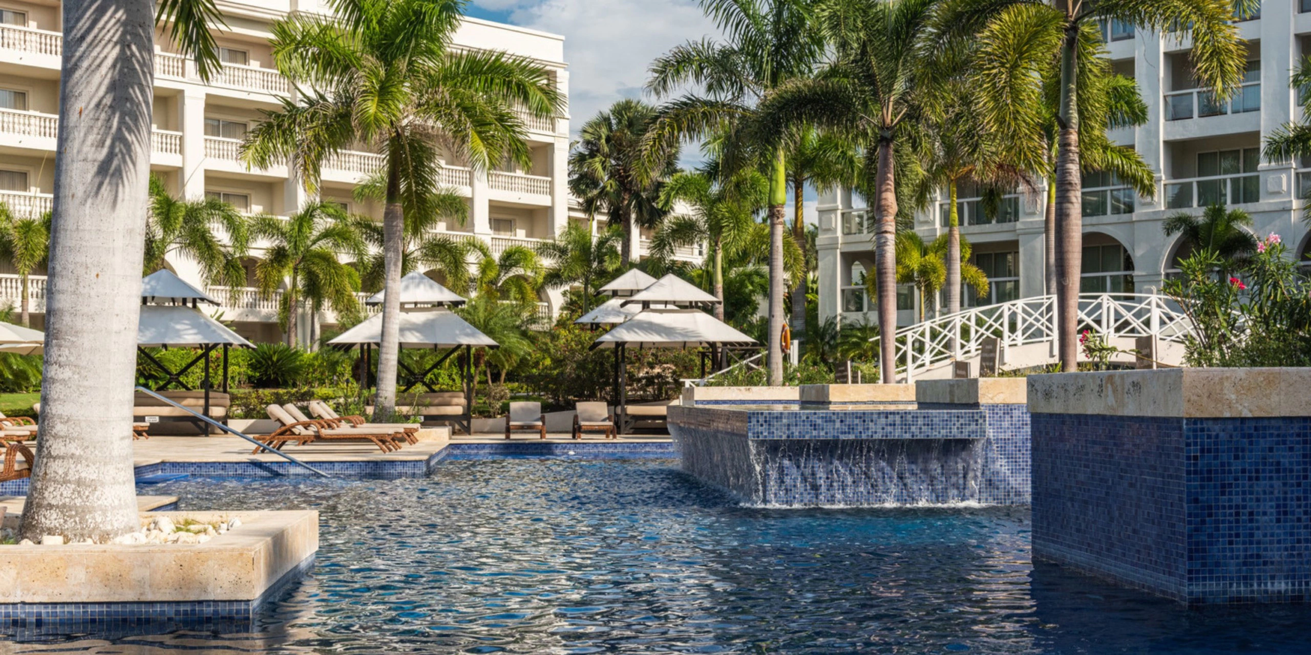 Expansive resort pool surrounded by palm trees and luxury accommodations at Hyatt Zilara Rose Hall.