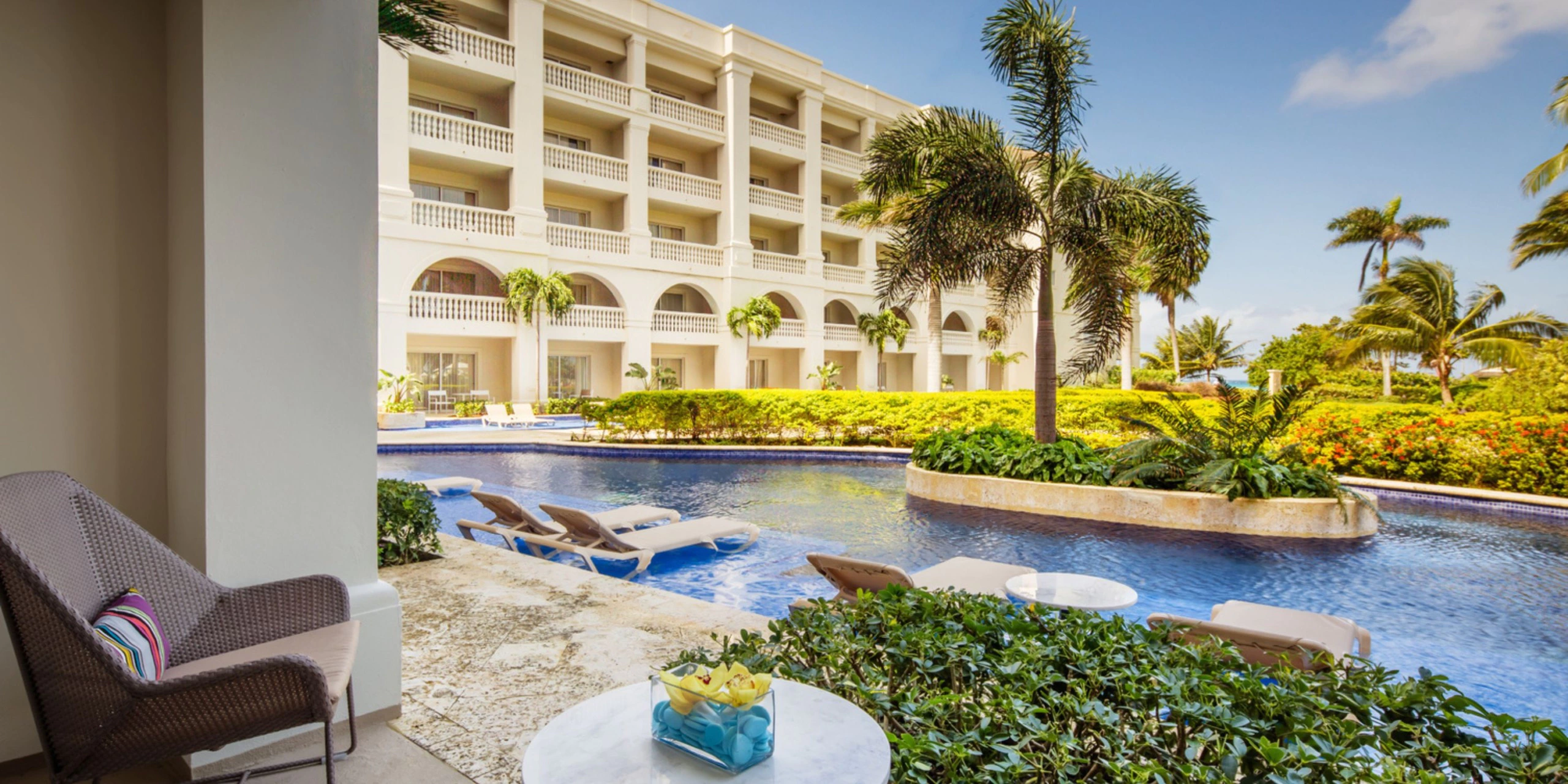 Swim-up suite patio overlooking a lazy river-style pool and tropical gardens at Hyatt Zilara Rose Hall in Montego Bay.